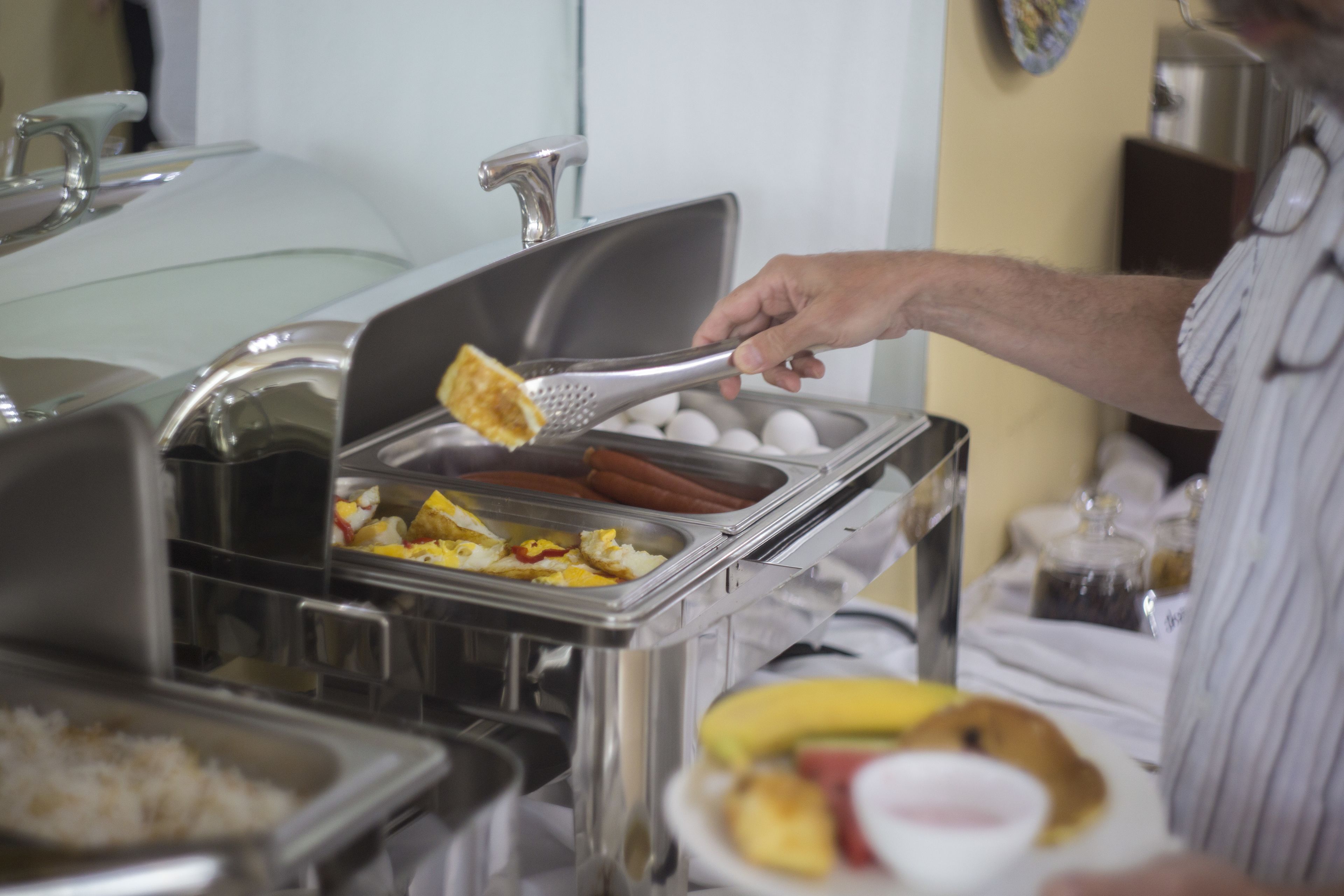 A buffet setup with various food items and a person serving food.
