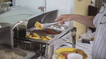 A buffet setup with various food items and a person serving food.