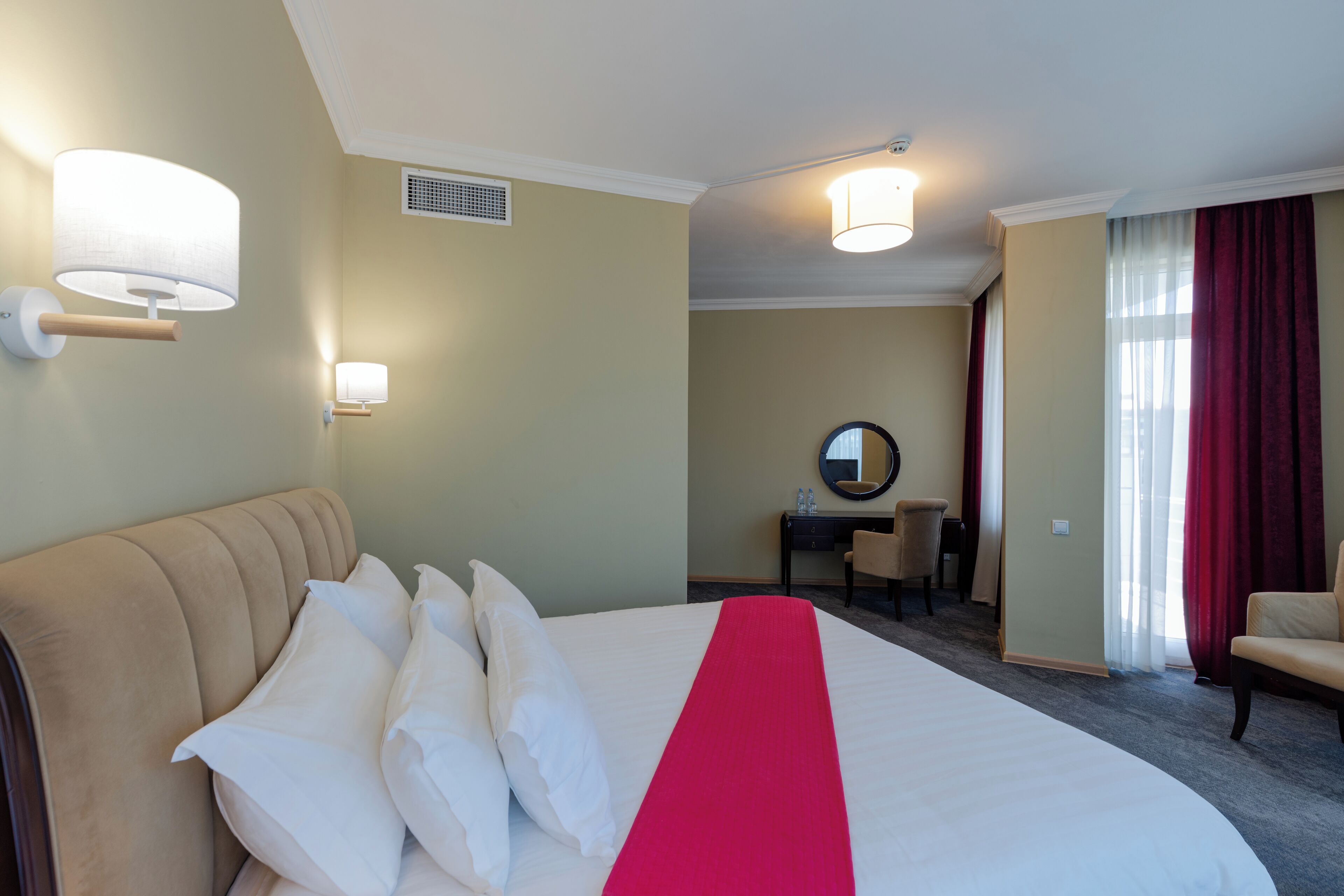 Quarto de hotel com uma cama grande, uma escrivaninha, uma cadeira e um espelho.
