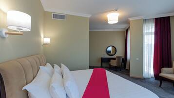 Quarto de hotel com uma cama grande, uma escrivaninha, uma cadeira e um espelho.