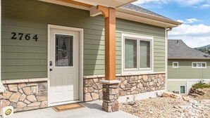 A house with a stone foundation, a white door, and the number 2764 on the side.