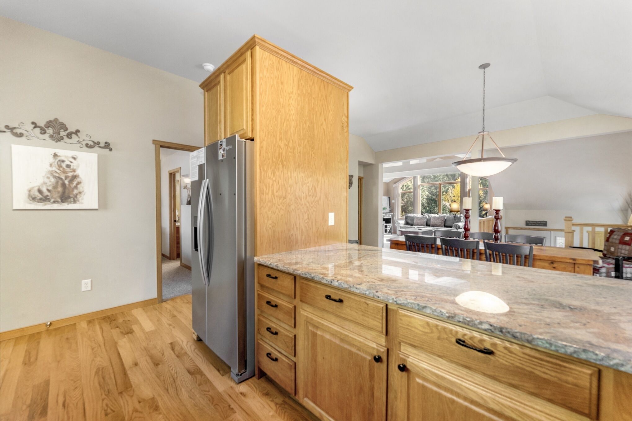 A kitchen with wooden cabinets, a granite countertop, and a stainless steel refrigerator.