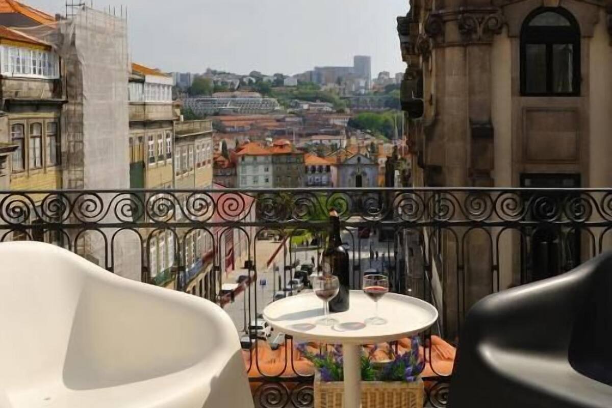 A terrace with a table and chairs, overlooking a cityscape with historic buildings.