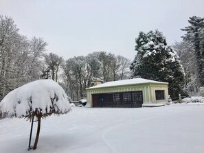 A snow-covered landscape with a single-story building featuring a garage.