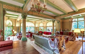 A spacious room with a large sofa set, multiple chairs, and a chandelier.