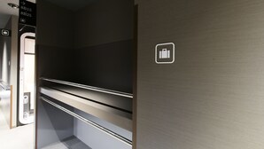 A hotel room with a minimalist design, featuring a built-in wardrobe with multiple shelves and a door leading to a bathroom. - FIRST CABIN Kyoto Kawaramachi Sanjo (Kyoto)