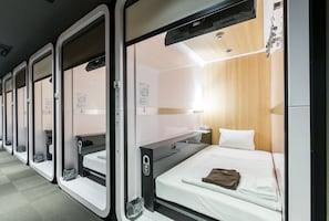 Filetta di letti singoli in un vagone treno con rivestimenti in legno e un tavolino con lampada.