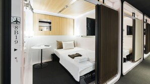 A modern hotel room with a bed, bedside table, and a small round table. - FIRST CABIN Kyoto Kawaramachi Sanjo (Kyoto)