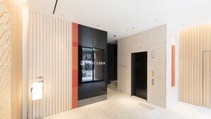 A modern hotel lobby with a central staircase, a reception desk, and a sign for the first cabin. - FIRST CABIN Kyoto Kawaramachi Sanjo (Kyoto)