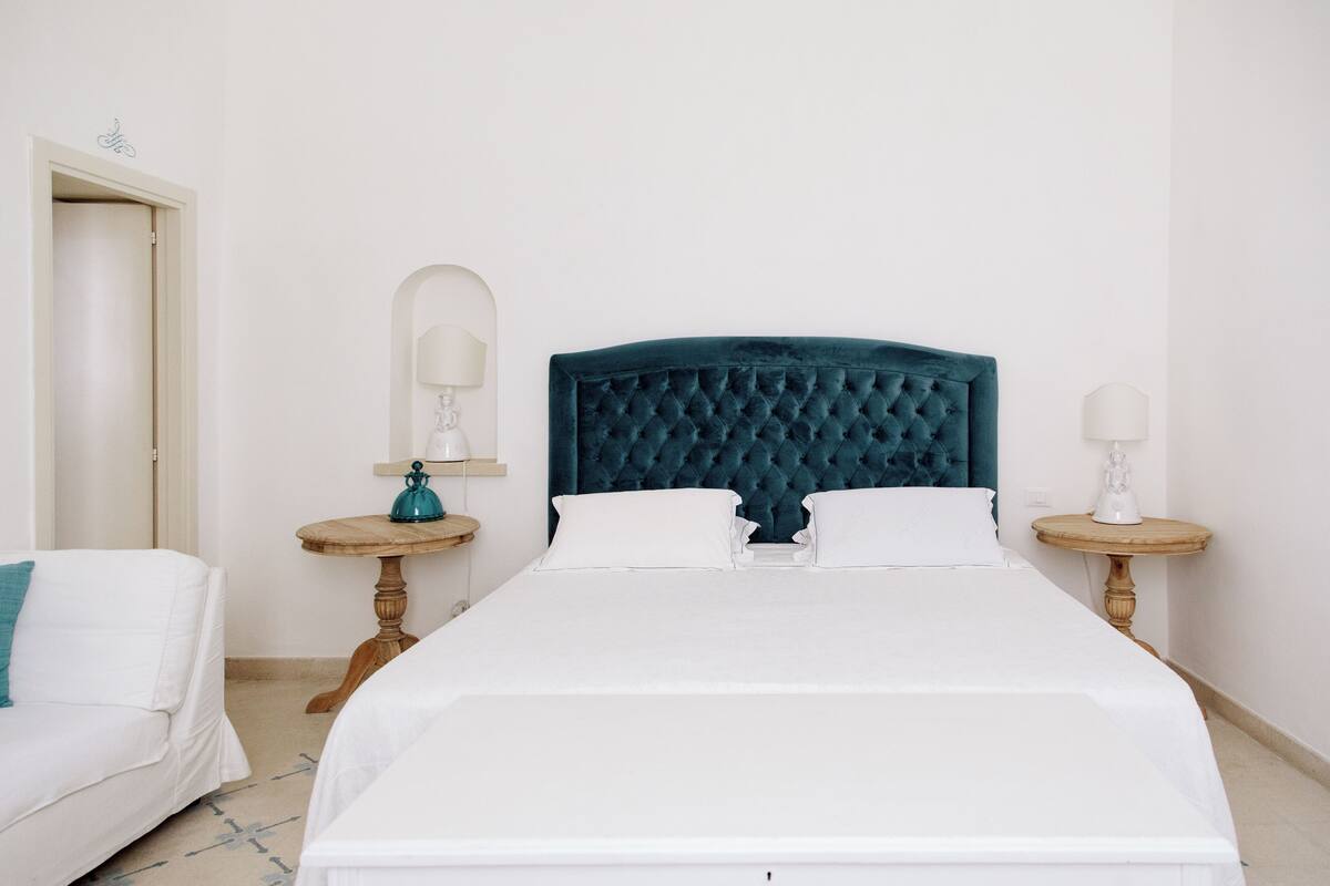 A neatly arranged bedroom with a large bed, two bedside tables, and a door.