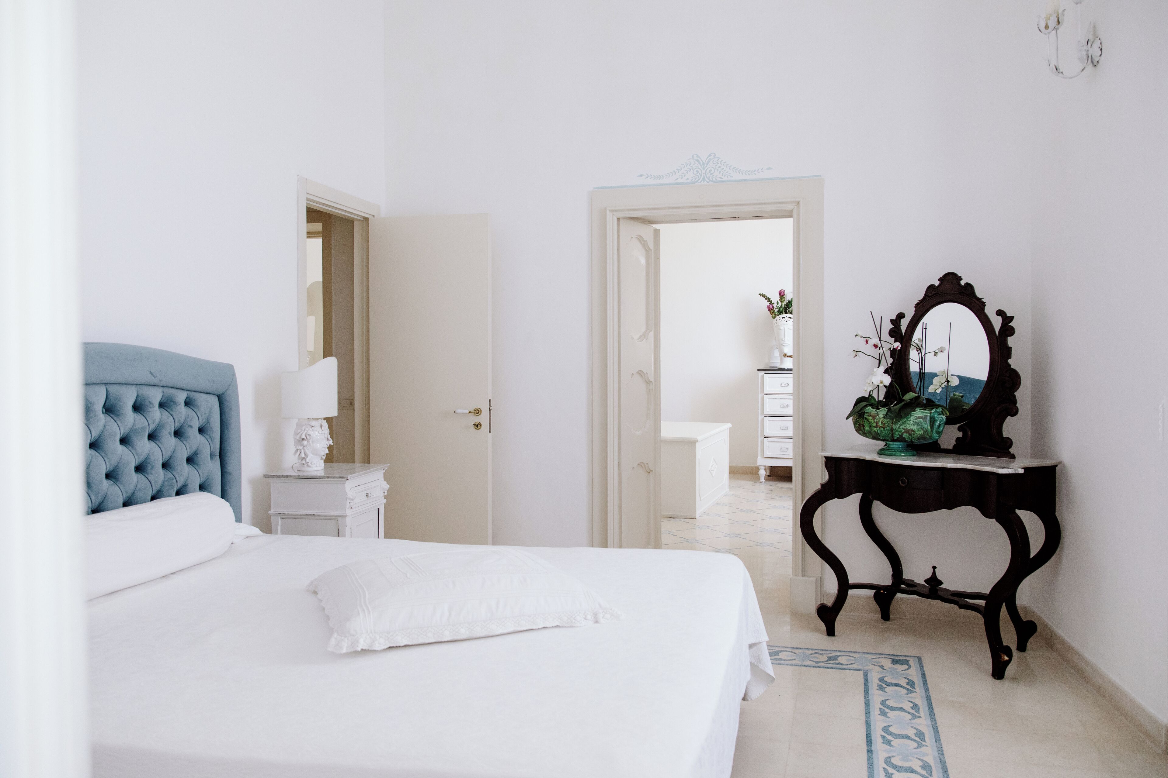 Une chambre à coucher avec un grand lit, une table de chevet avec une lampe, une commode et un miroir au mur.