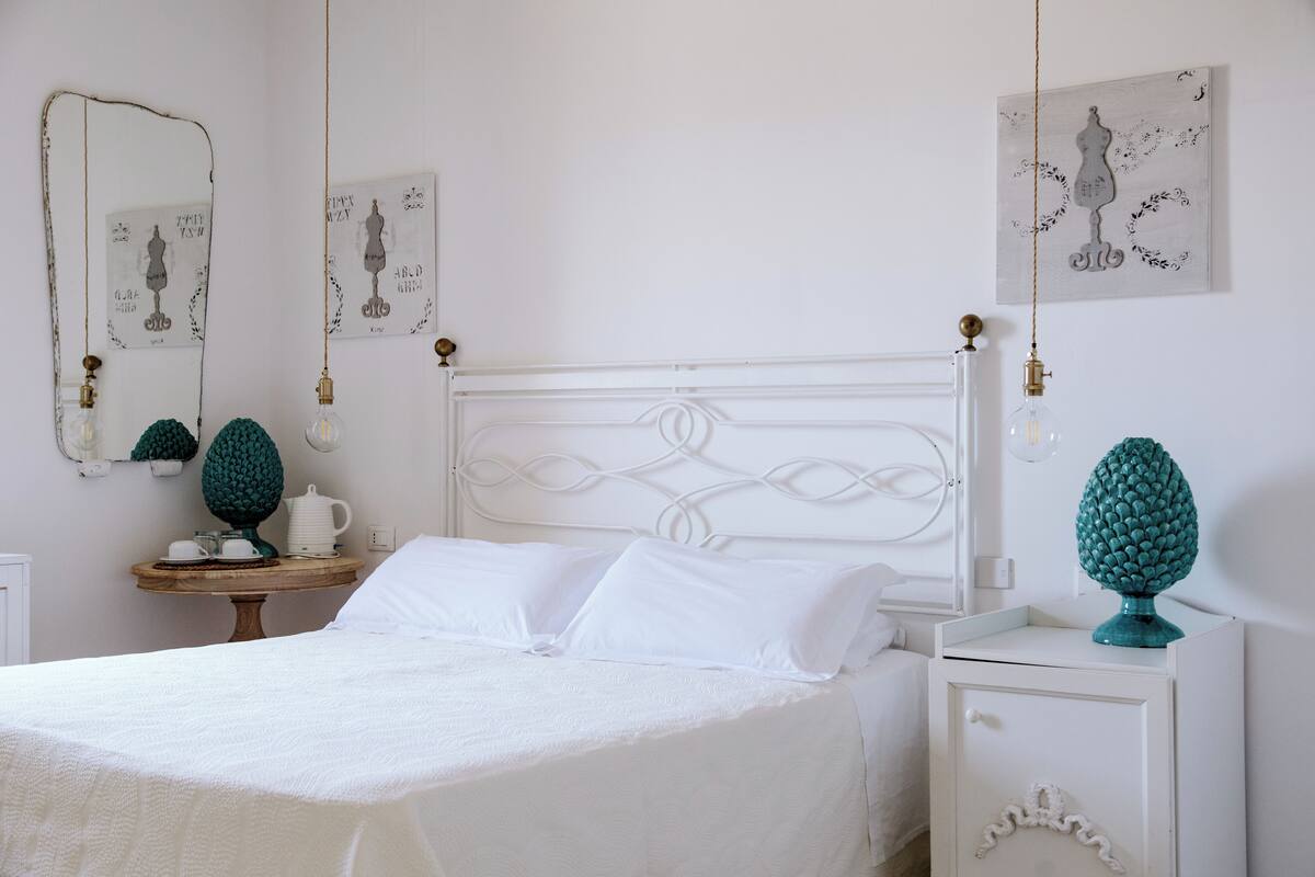 A neatly arranged bedroom with a bed, bedside tables, and wall art.
