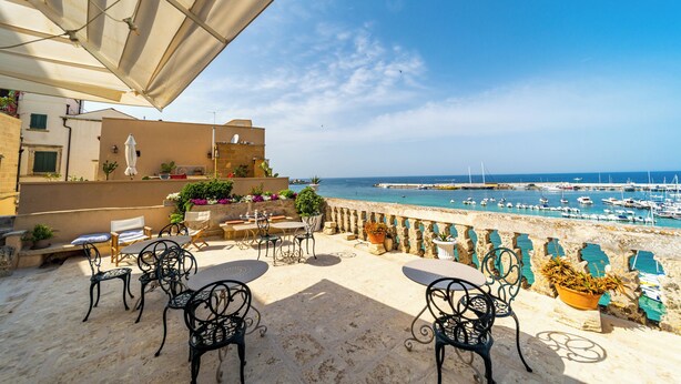 A terrace with outdoor seating and a view of the sea.