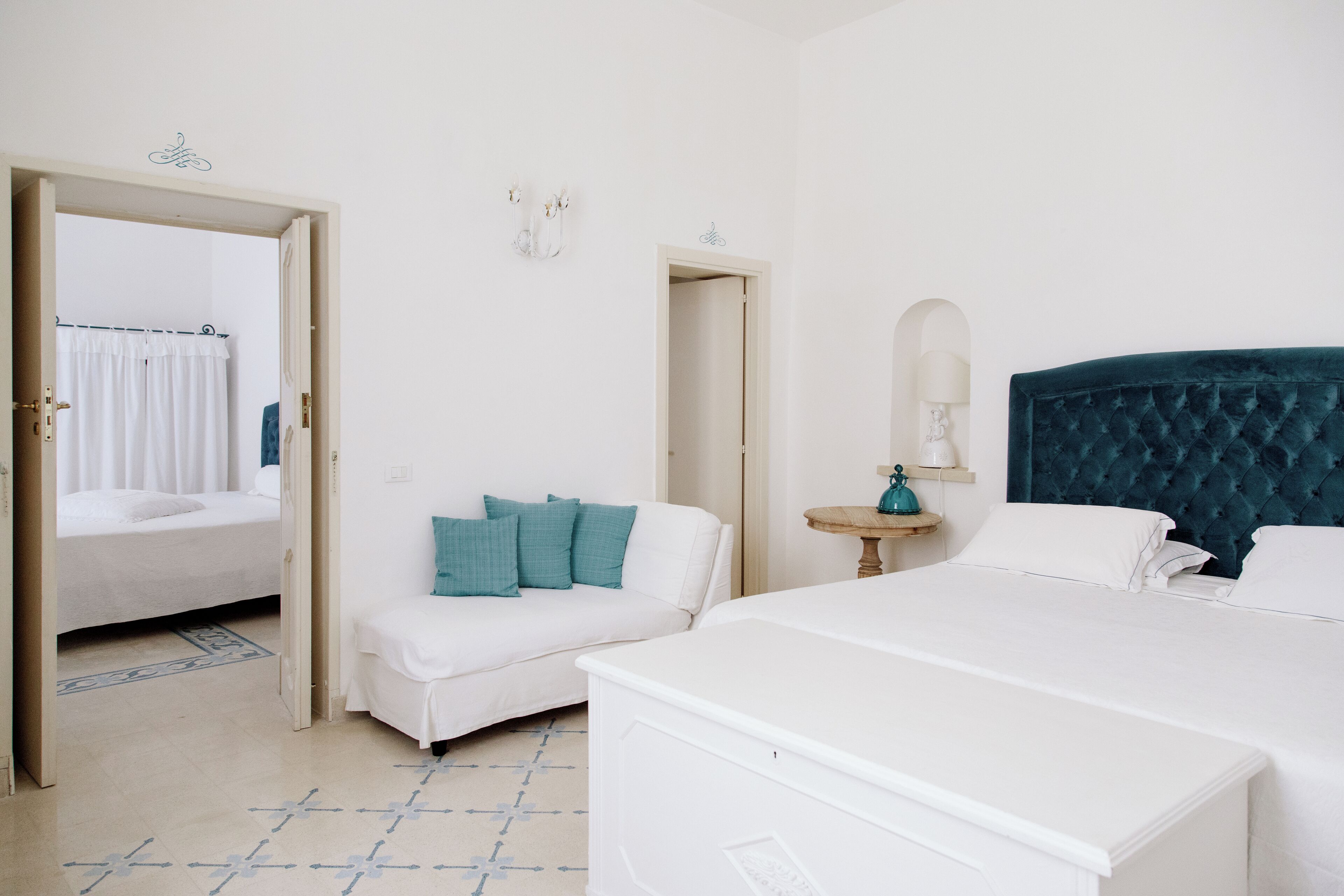 Hotelkamer met een bed, een bank, een klein tafeltje en een zichtbare badkamer door een geopende deur.