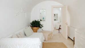 A minimalist bedroom with a bed, a bedside table, a plant, and a white wardrobe.