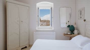 Una camera da letto con un armadio grande, un tavolino con una lampada e una finestra vista edifici.