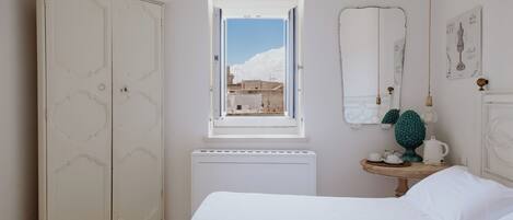 Una camera da letto con un armadio grande, un tavolino con una lampada e una finestra vista edifici.
