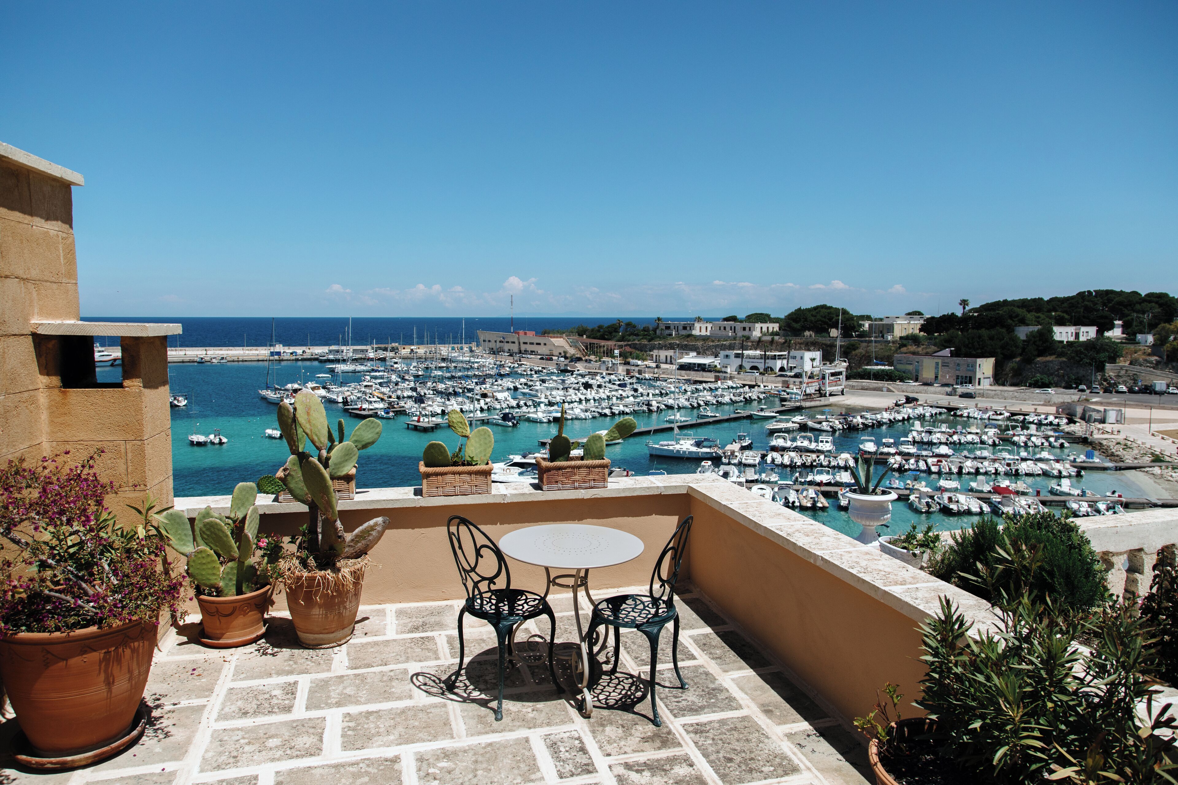 A terrace with a table and chairs overlooking a marina with numerous boats.