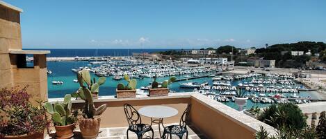 A terrace with a table and chairs overlooking a marina with numerous boats.