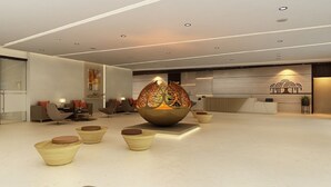 Un moderno vestíbulo con un cuenco decorativo central, zonas de estar y un mostrador de recepción.