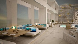 Un restaurante moderno con mesas largas comunitarias, cojines azules y una zona de piscina.