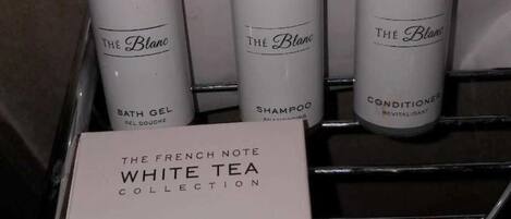 Un portasciugamani in bagno con tre prodotti della linea The French Note White Tea Collection: bagnoschiuma, shampoo e balsamo.