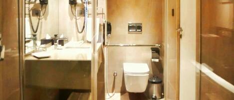 Baño compacto con mampara de vidrio, inodoro, lavabo y zona de ducha.