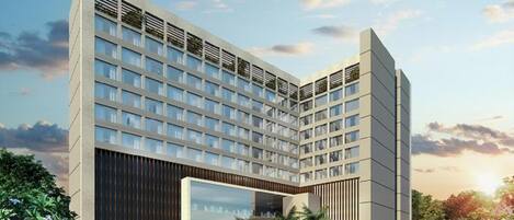 A modern hotel with a large central atrium, multiple floors, and a landscaped courtyard with outdoor seating.