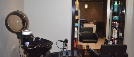 A salon with a hairdryer, mirrors, and a seating area.