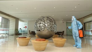 A person in protective gear cleaning a lobby area with a large decorative bowl and several smaller bowls. - Sayaji Vadodara (Vadodara)