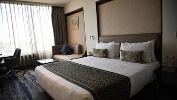 A hotel room with a large bed, a desk, and a chair.
