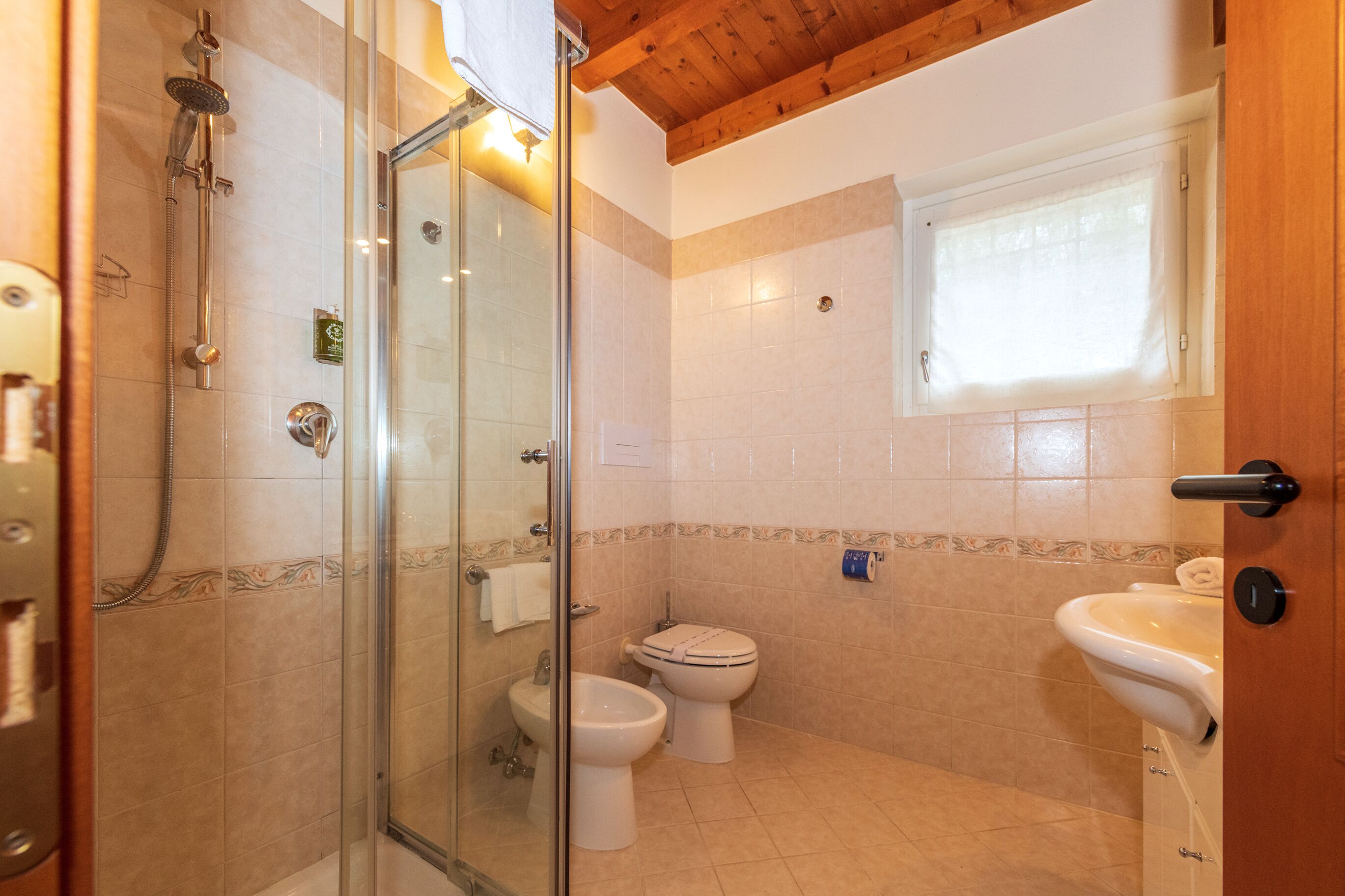 A bathroom with a glass-enclosed shower, a toilet, and a sink.