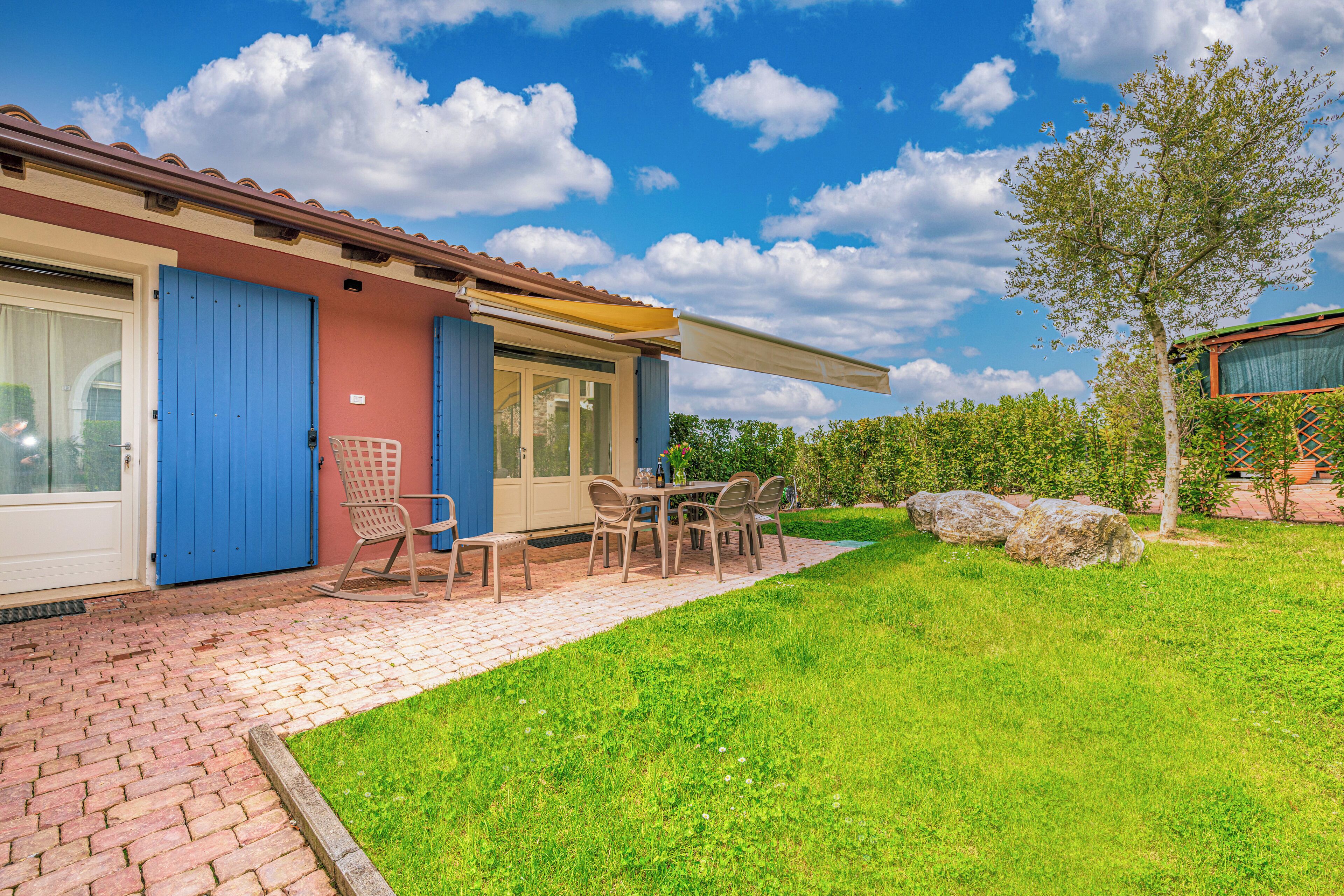 A house with a patio, a table with chairs, and a blue door.