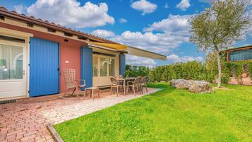 A house with a patio, a table with chairs, and a blue door.