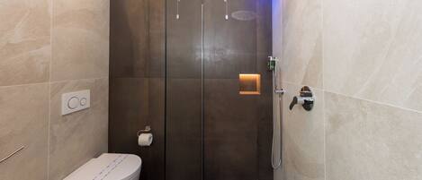 Un baño moderno con cabina de ducha de vidrio, inodoro y bidé.