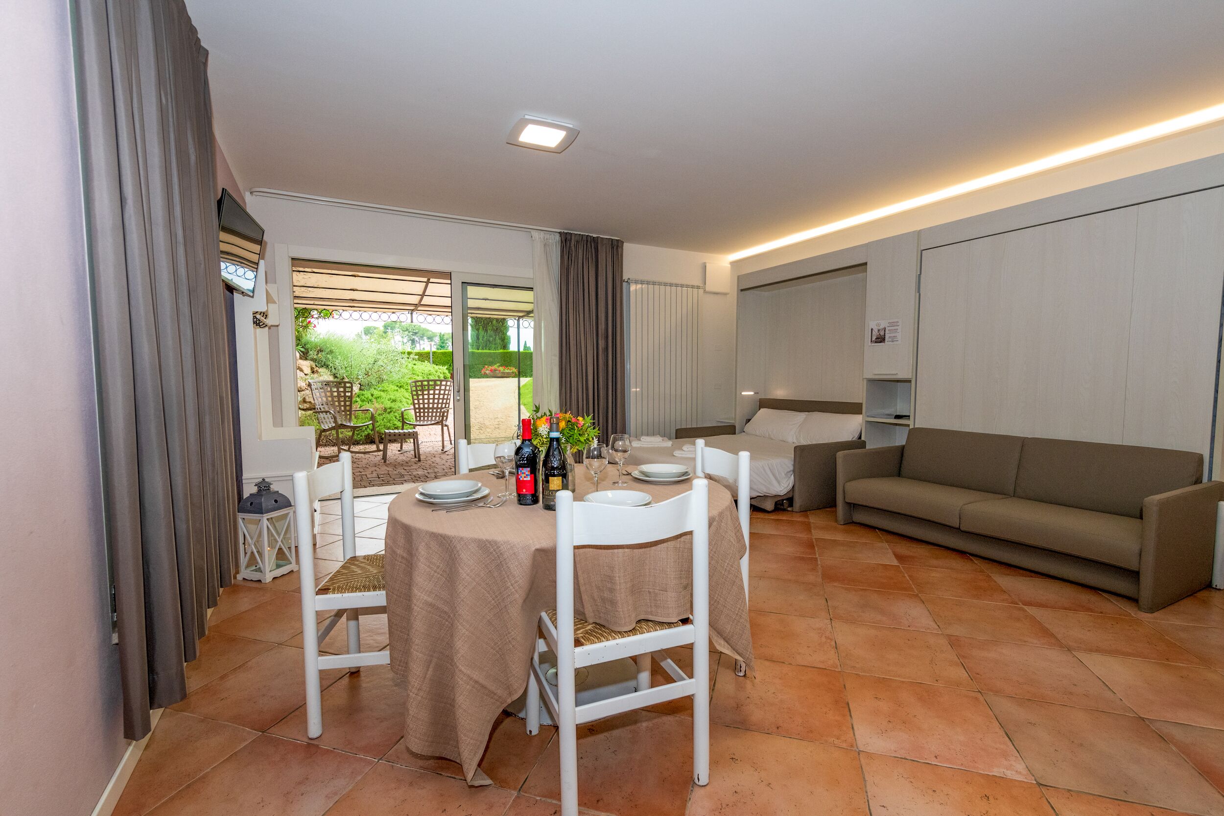 A dining area with a table set for four, a sofa, and a view of the garden.