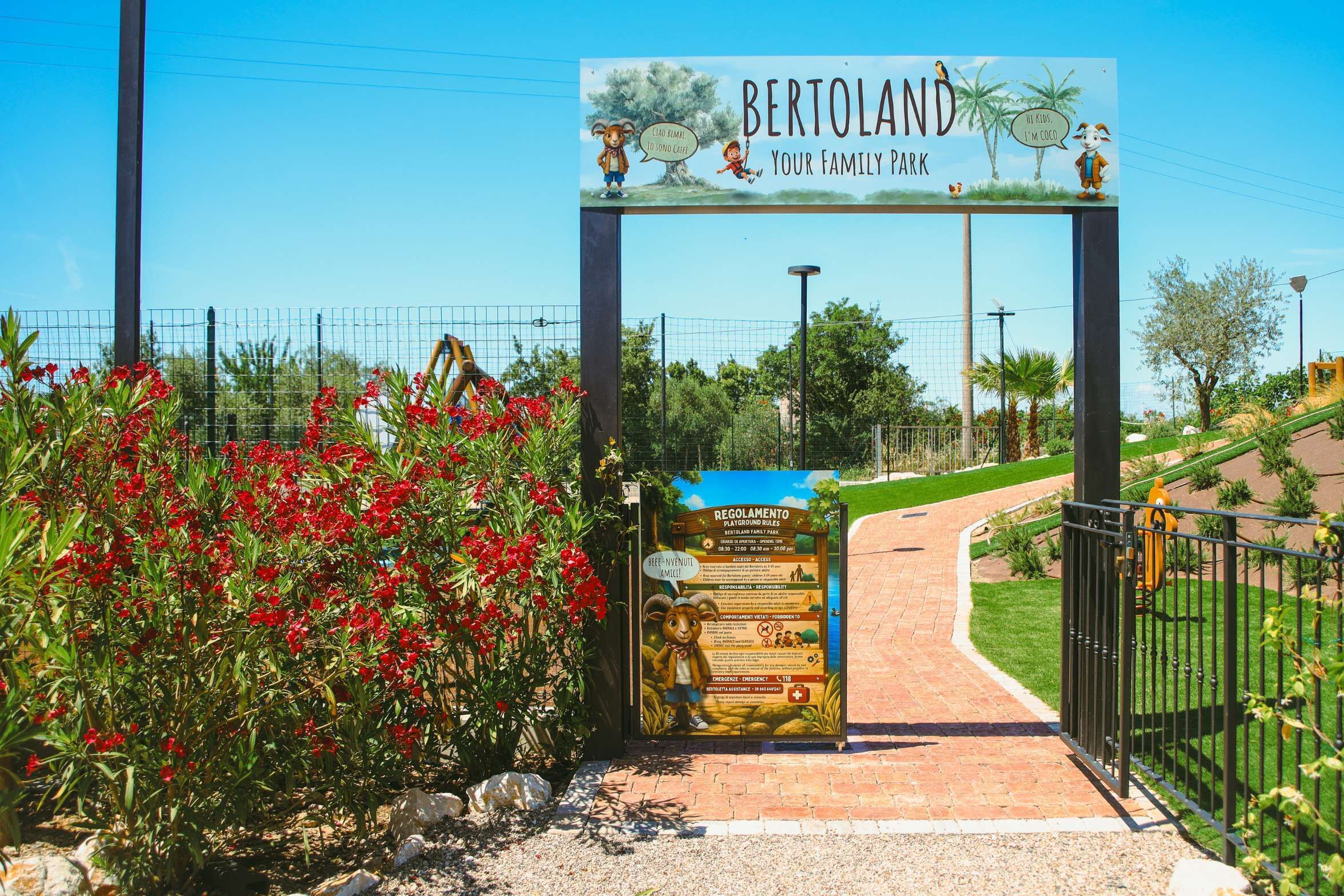 A park entrance with a sign reading 'BERTOLAND Your Family Park' and a playground rules sign.