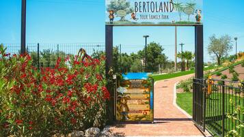 A park entrance with a sign reading 'BERTOLAND Your Family Park' and a playground rules sign.