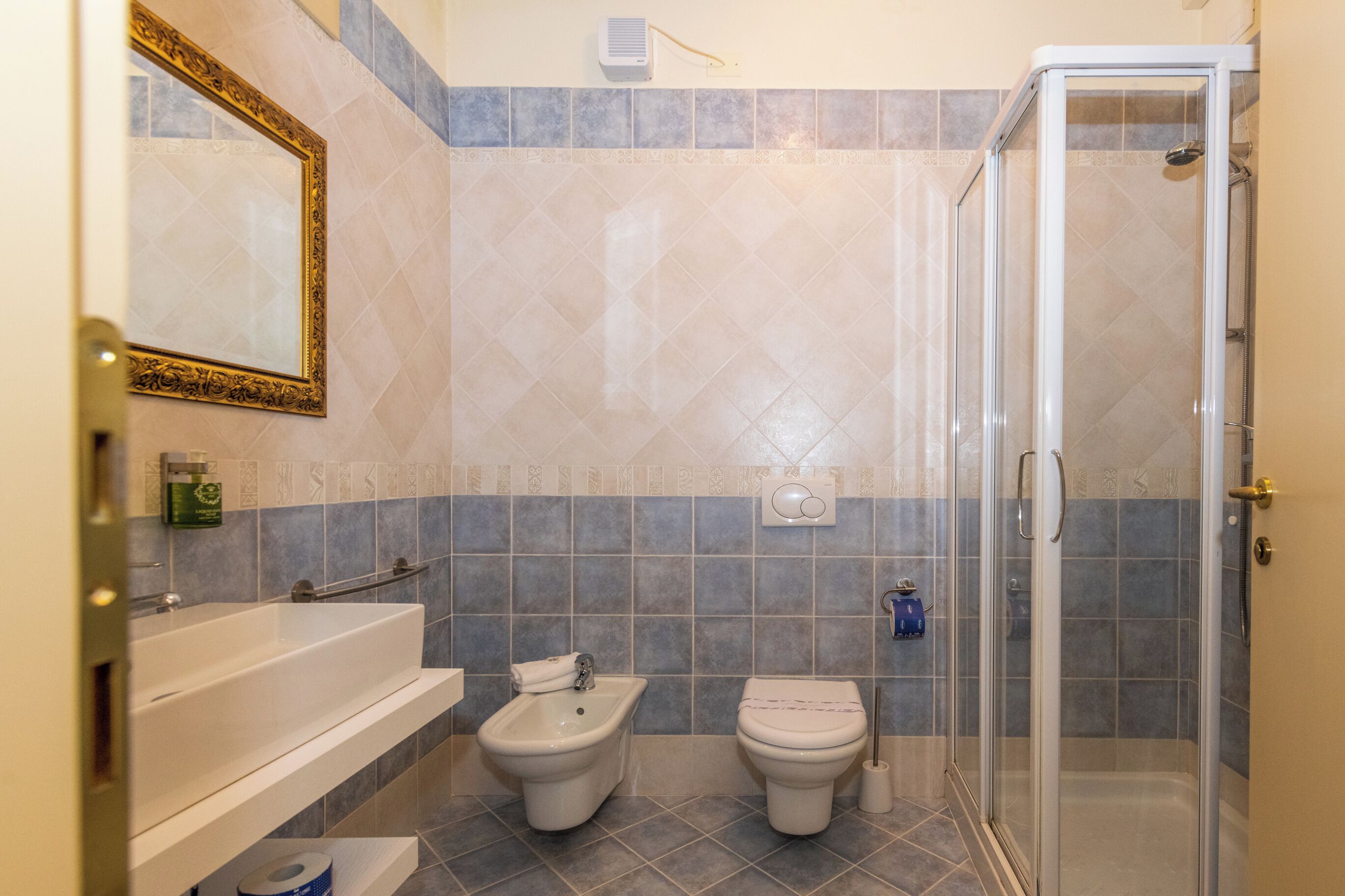 A bathroom with a bathtub, bidet, toilet, and a glass-enclosed shower.