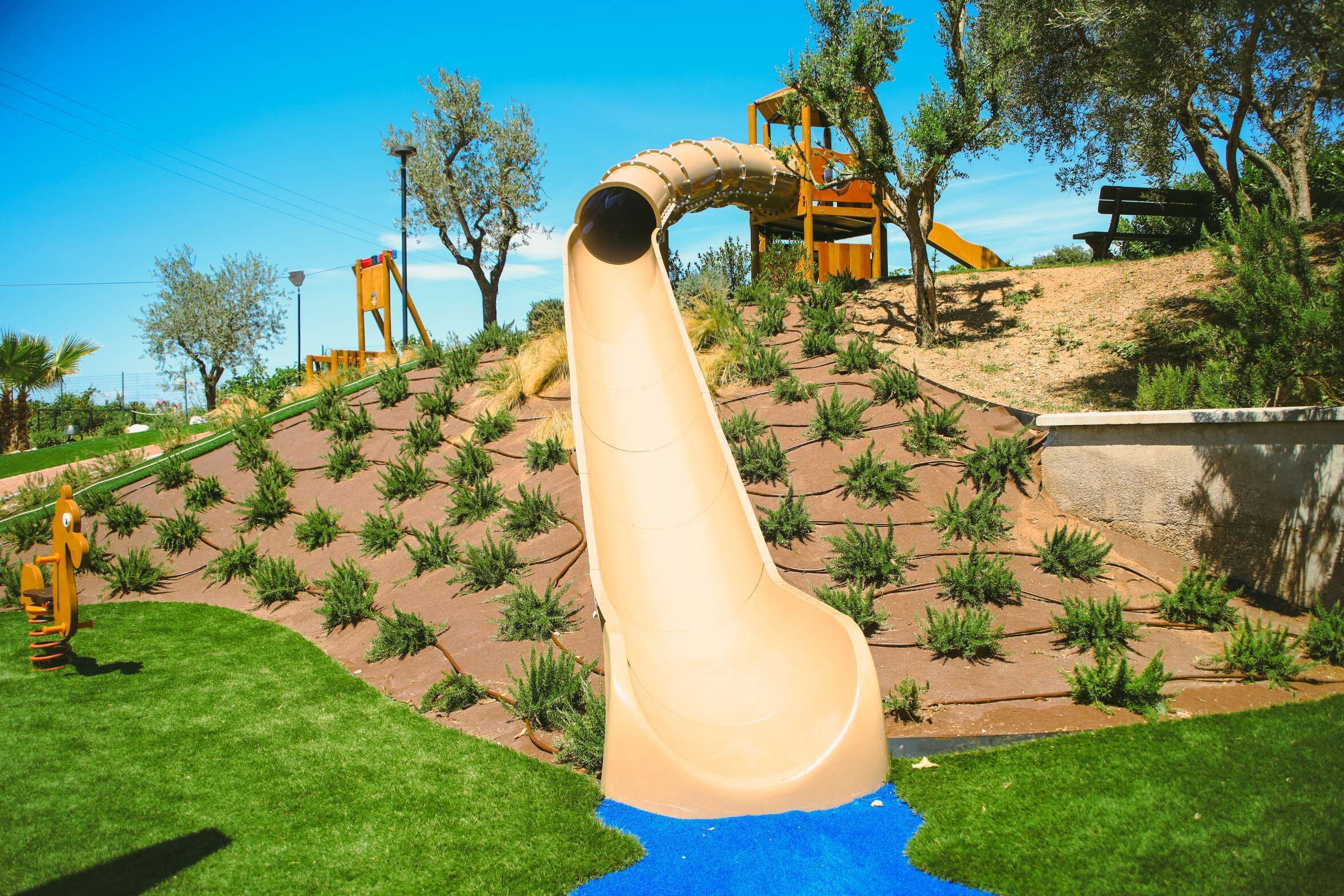 A playground with a slide, climbing area, and a wooden structure.