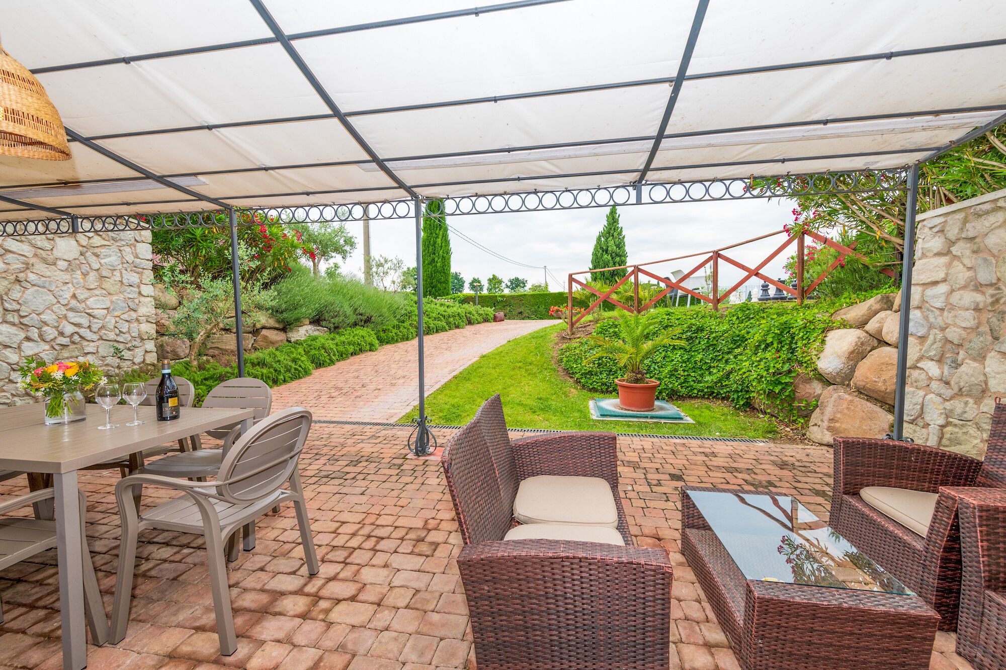 An outdoor patio area with wicker furniture, a table with drinks, and a stone wall.