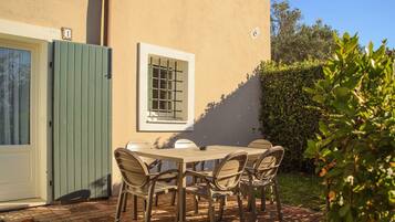 A patio with a table and chairs, a green gate, and a window with bars.