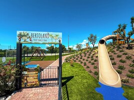 Un parque infantil con tobogán, columpios y un letrero que dice 'Bertoland Parque Familiar'.