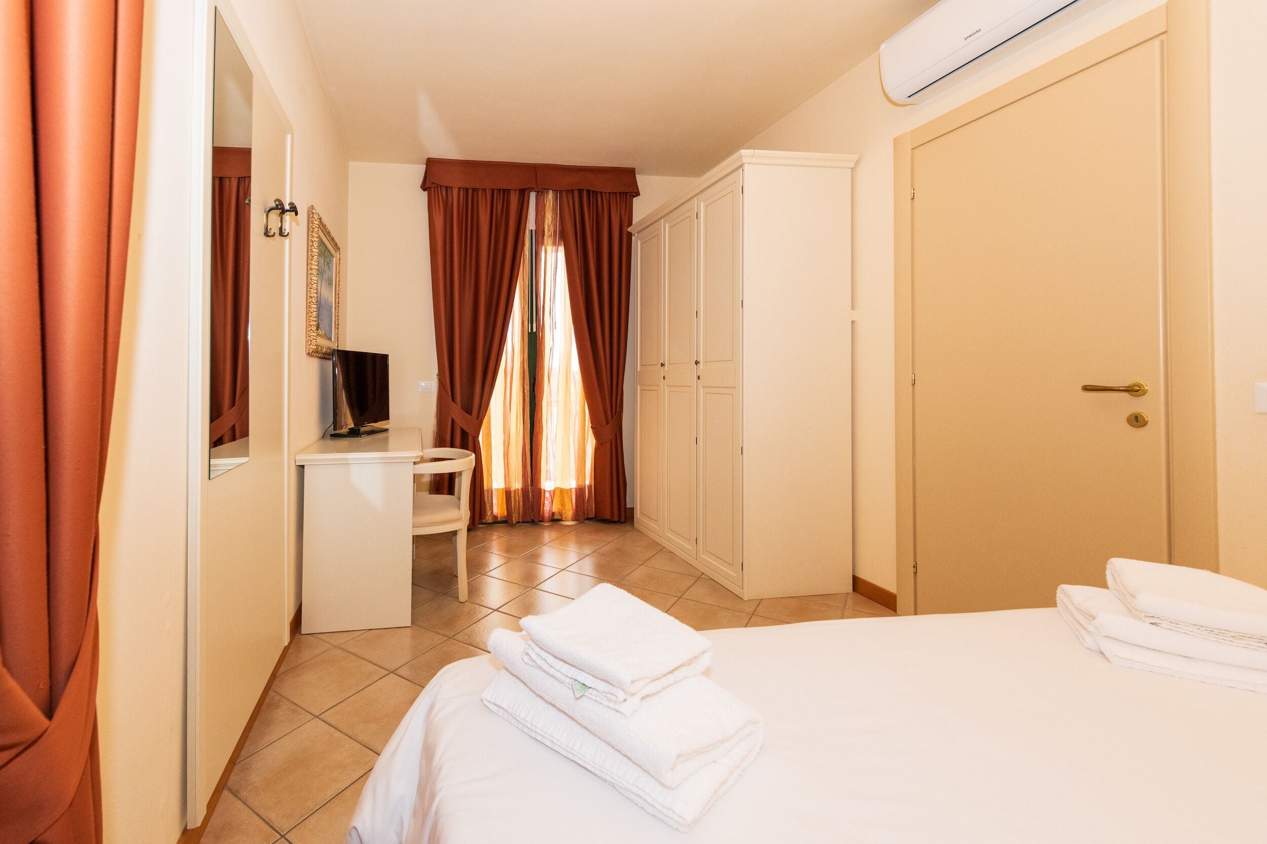 A hotel room with a bed, a desk, a wardrobe, and a bathroom.