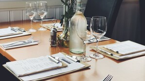 A dining table set with menus, wine glasses, a bottle of water, and a small vase with flowers. - Dragsö Camping & Stugby (Karlskrona)