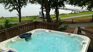 A hot tub with a wooden deck and a view of a lake with boats. - Dragsö Camping & Stugby (Karlskrona)