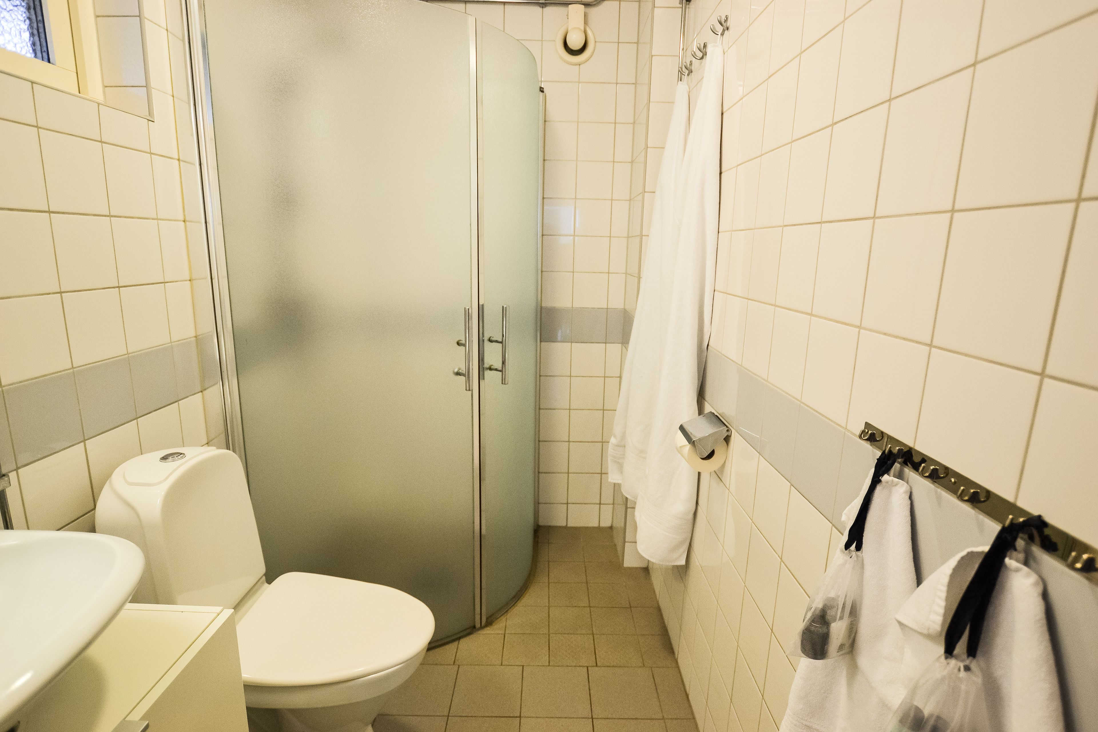 A bathroom with a toilet, sink, and shower stall.