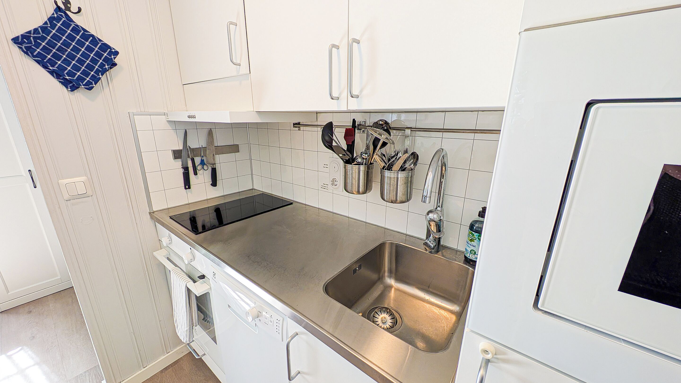 Una cucina moderna con mobili bianchi, un lavello in acciaio inossidabile e un forno integrato.