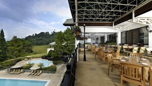 A pool area with lounge chairs, a dining area with tables and chairs, and a view of the surrounding landscape. - Berjaya Hills Golf & Country Club (Bukit Tinggi)