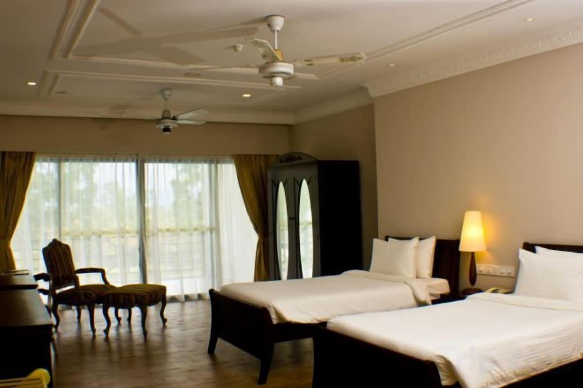 Een hotelkamer met twee bedden, een bureau, een stoel, een televisie en een lamp.